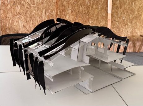 1:50 section model of Maison Peplum: white card building cut open to show two floors and a stair, with curved black card fins hung over the roof.